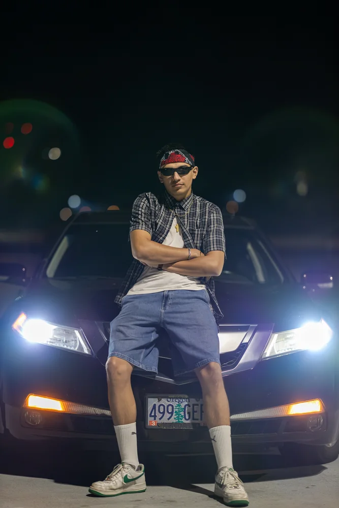 Night portrait seated on a car with its headlights on