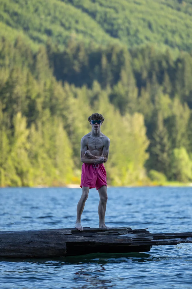 Portrait standing on a log beside a forest lake