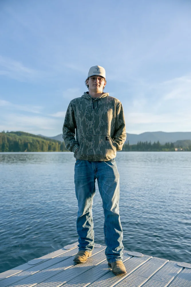 Portrait in a green sweatshirt on a lakeside dock