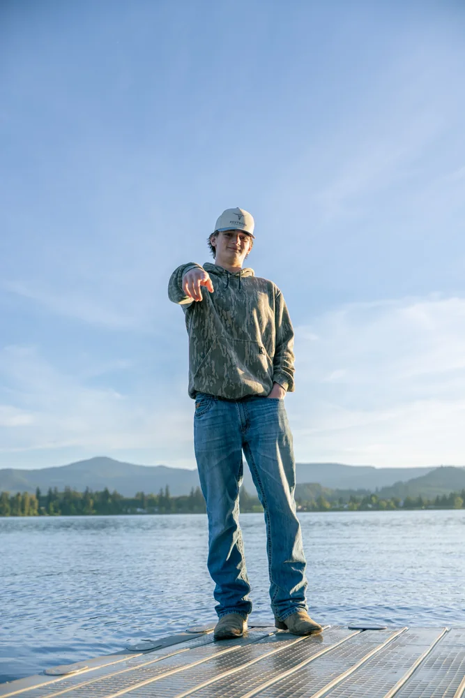 Playful portrait pointing toward the camera on a dock