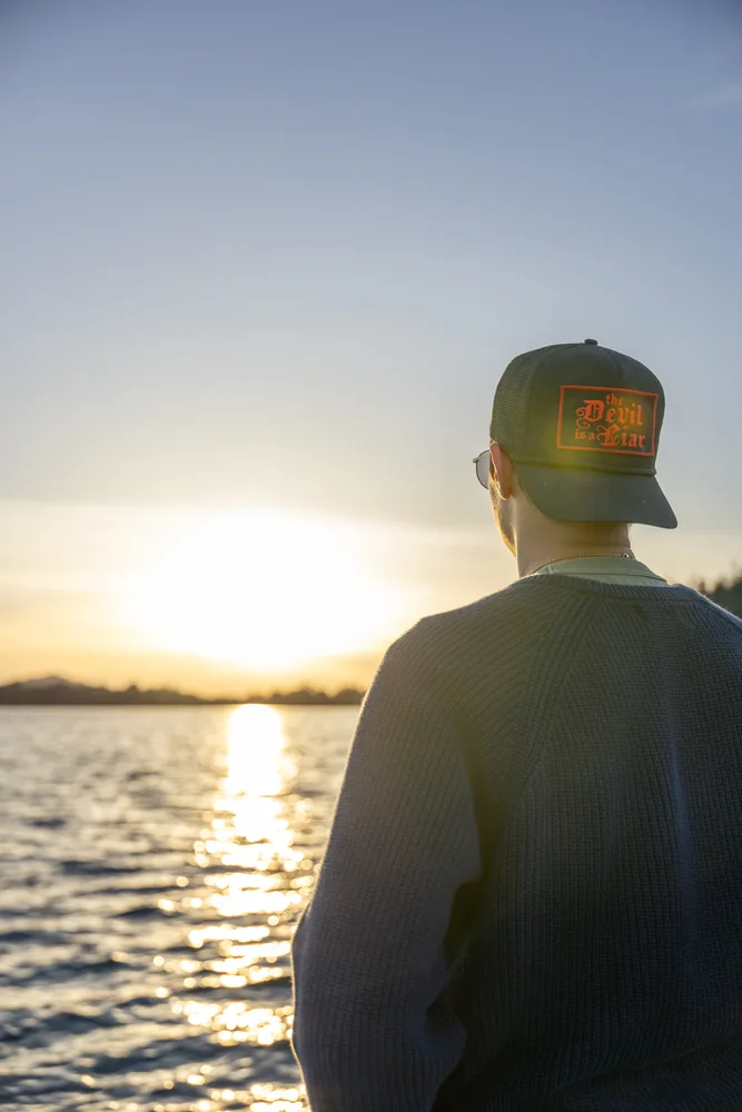 A person looking across the lake toward the setting sun
