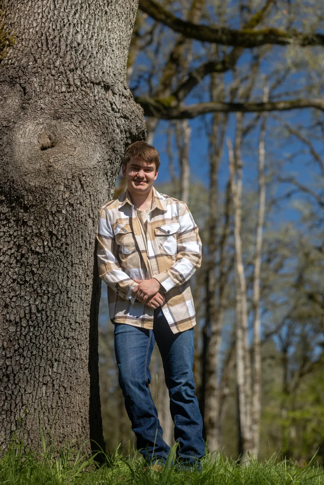 Portrait leaning against a tree in the woods