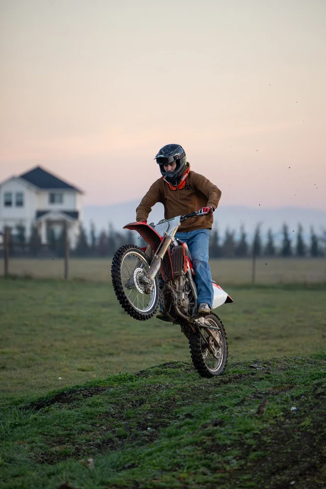Motocross rider lifting the front wheel in evening light