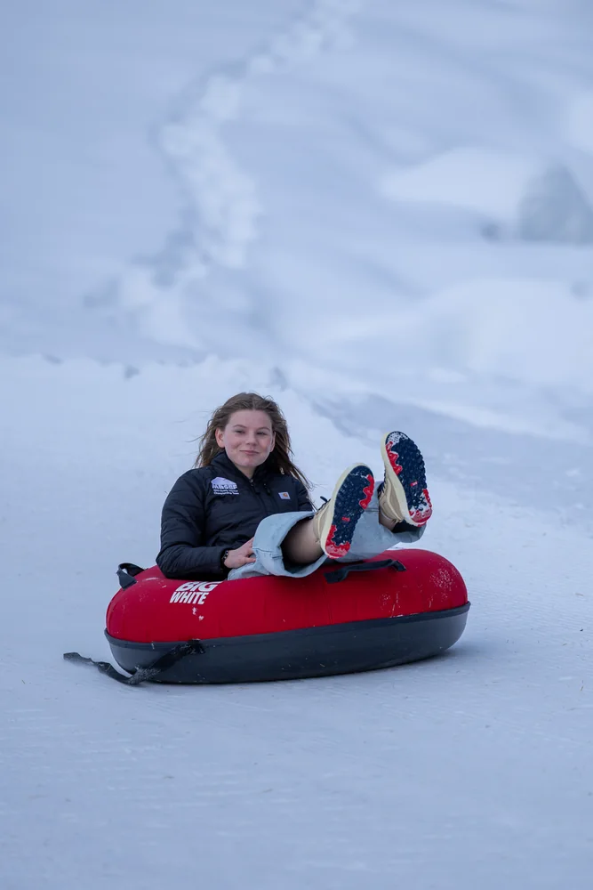 A person riding a red snow tube
