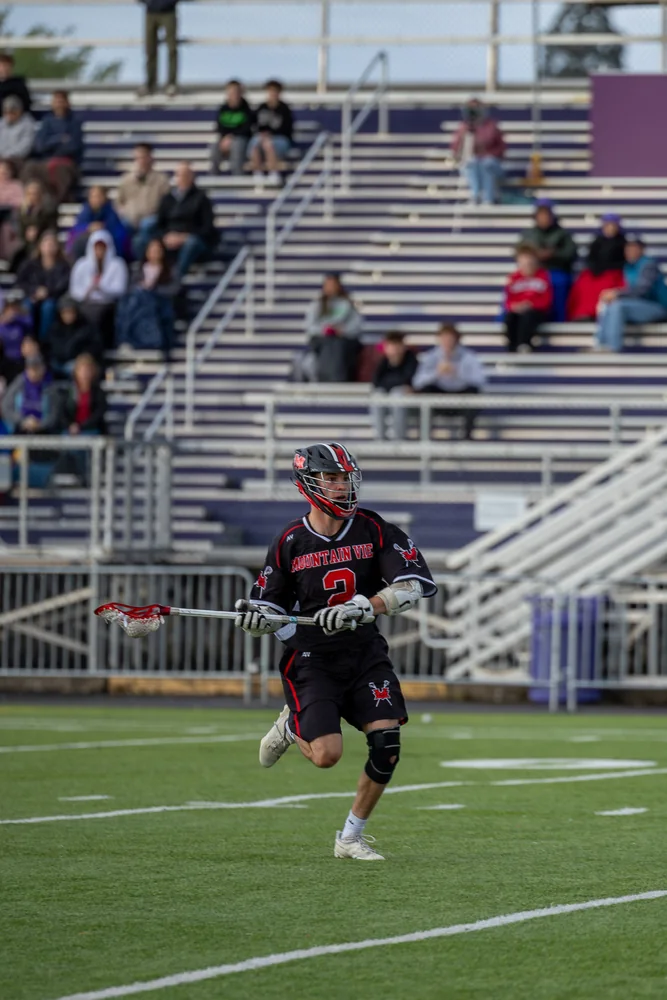 Lacrosse player running in front of stadium bleachers