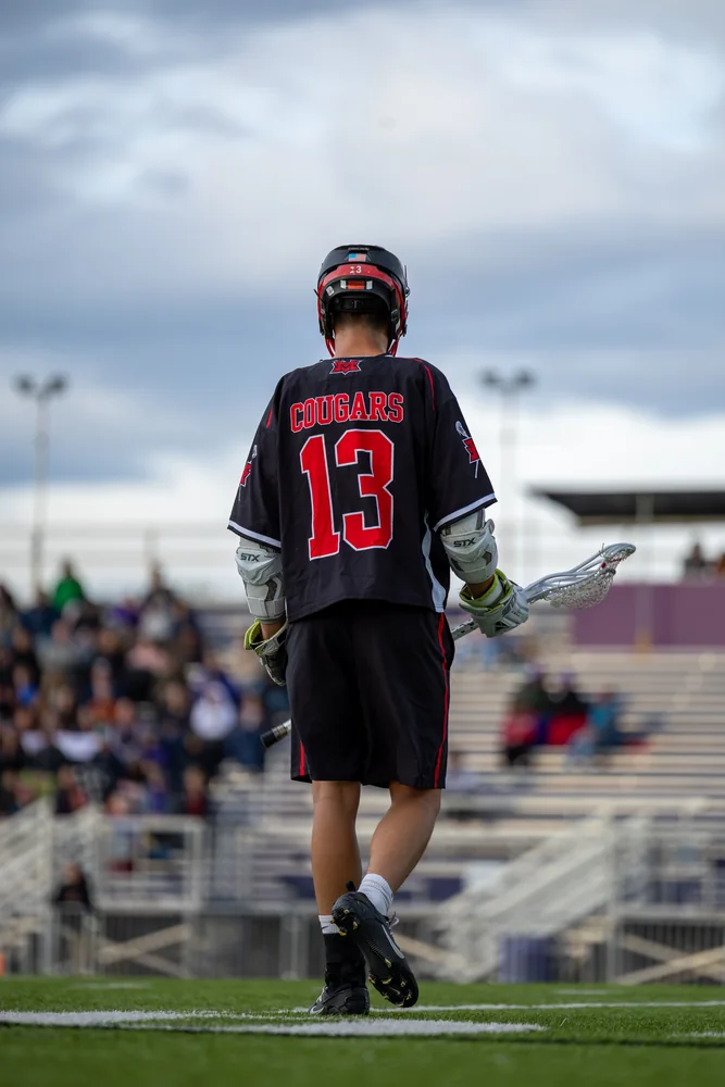 Lacrosse player wearing number 13, seen from behind