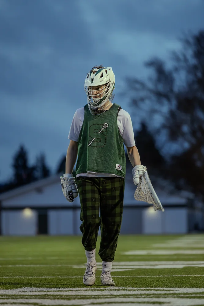 Lacrosse player standing with a stick at dusk