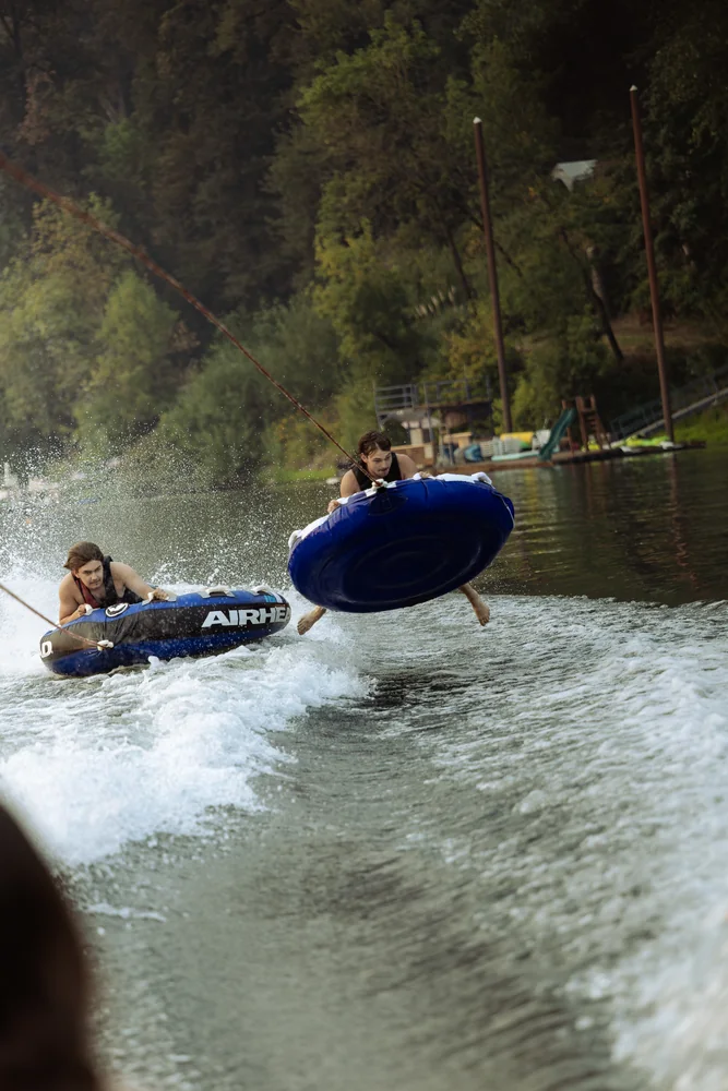 Riders on an inflatable tube skimming across the lake