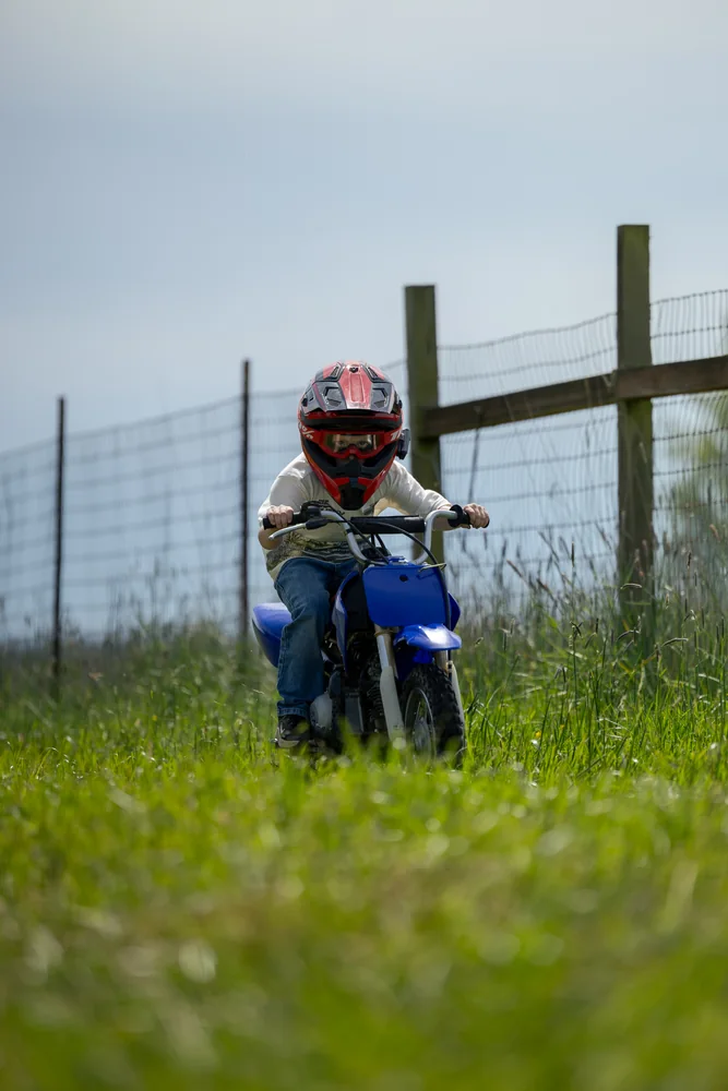 Helmeted motocross rider beside a wooden fence
