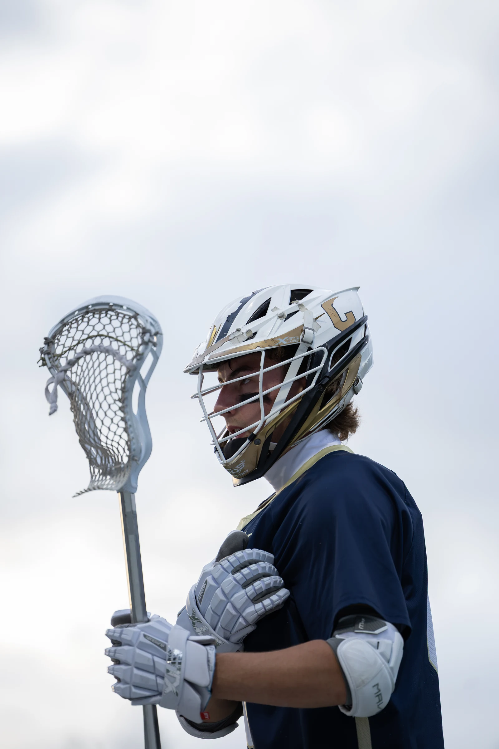 Lacrosse player holding a stick, photographed in profile